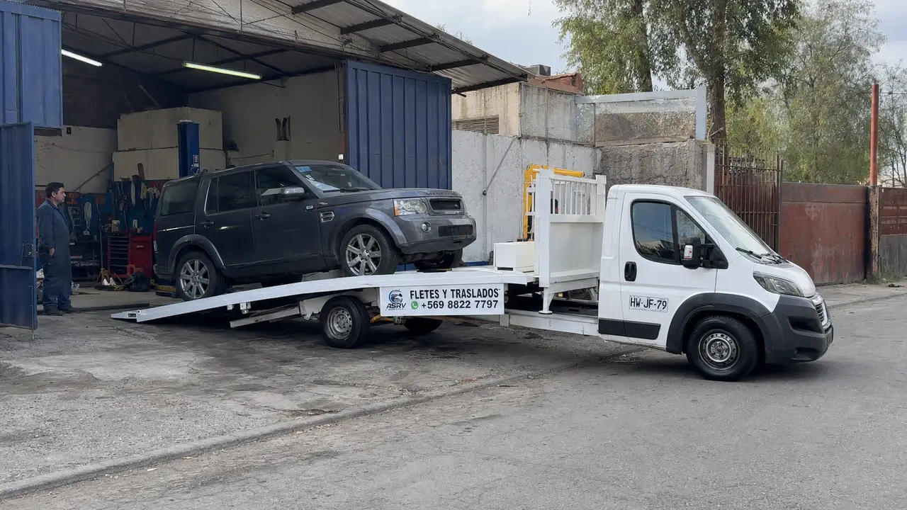 Grúa de plataforma de ASVR dejando un auto en la entrada de un taller mecánico en Santiago