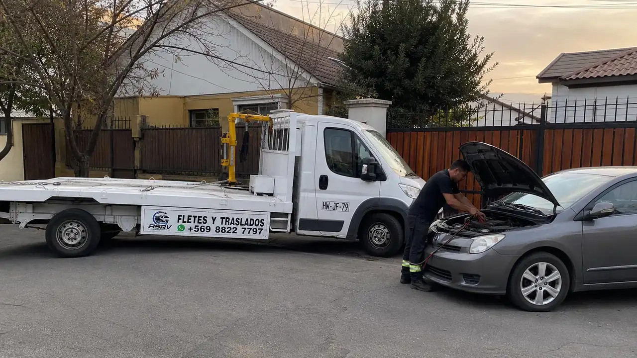 Operador de ASVR Grúas conectando pinzas de puente de batería a un auto en una calle de Santiago